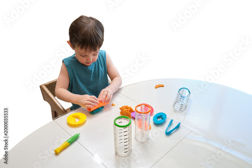 Little child playing with modeling clay at table. Toddler learning to use plastic tools and sculpting dough. Creative activity for development and education in early childhood.