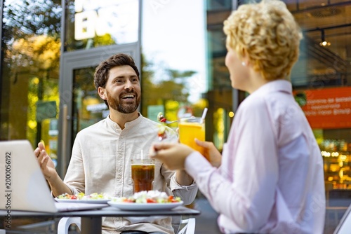 Fotografija A man and woman are laughing and talking while having lunch and drinks at an out