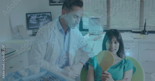 Leaning labcoat gloved dentist examining patient in teal at clinic holding mirror tray Xray overlay
