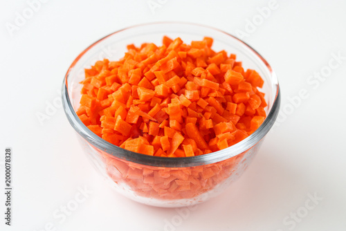 Konstfotografi A clear glass bowl of diced or chopped orange carrots, isolated on a white background