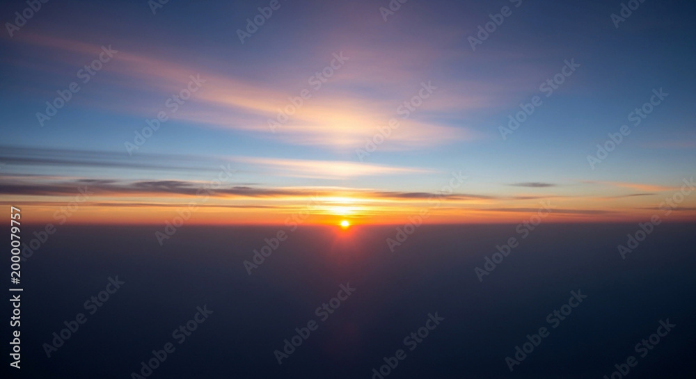 Fototapeta premium Vibrant sunset with orange sun and clouds in blue sky above sea or ocean horizon