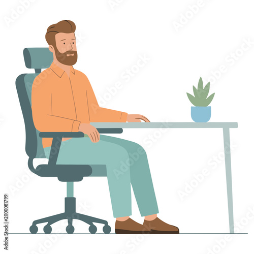 A man sits at a desk working on a computer with a plant nearby.