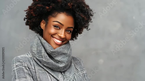 Young african female adult portrait in grey plaid coat and thick scarf soft expression studio backdrop
