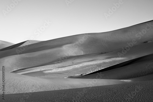 Φωτογραφία Black and white sand dunes with dramatic shadows and sweeping curves at Great Sa