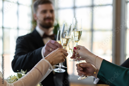 Fotografía Bride, groom, and guests clink champagne flutes during an indoor wedding toast w