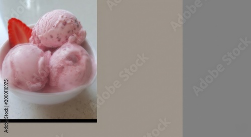 Creamy pink strawberry ice cream scoops with fresh sliced strawberry on a bright surface, offering a refreshing and sweet dessert treat.