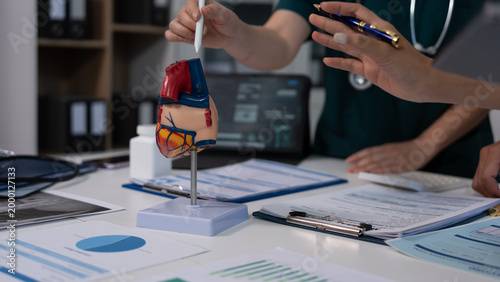 Obraz na plátne Anatomical heart and kidney models on a desk with medical charts, in a clinical office meeting with healthcare professionals discussing diagnostics and patient care