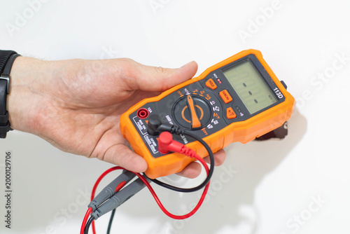Foto Close-up of a professional technician's hands using a digital multimeter to check the voltage in a power socket during home electrical repair or maintenance