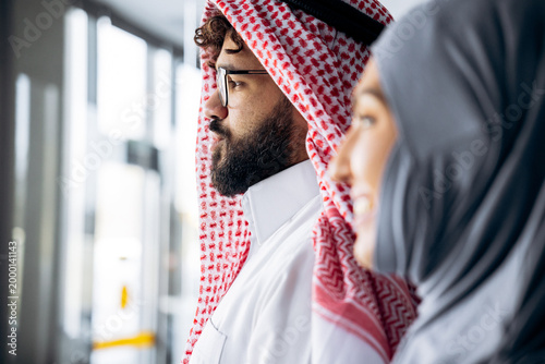 Bilde på lerret Arab man and woman, business professionals, standing together with a focused gaz
