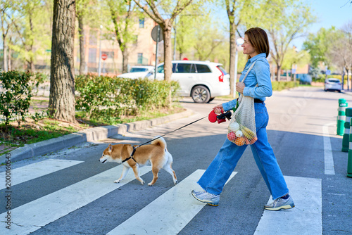 Mature woman walking dog and carrying groceries