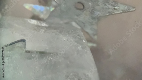 Abstract macro image of silver star sequins frozen in ice with dreamy blur and reflective textures for luxury, winter, and creative backgrounds.