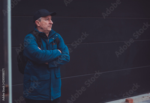 Thoughtful Mature Man with Backpack Looking at River. Active Lifestyle and Travel Concept