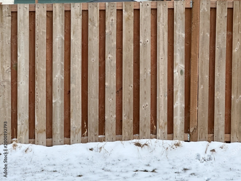Fototapeta premium Wood privacy fence detail with vertical boards showing residential fencing construction in winter