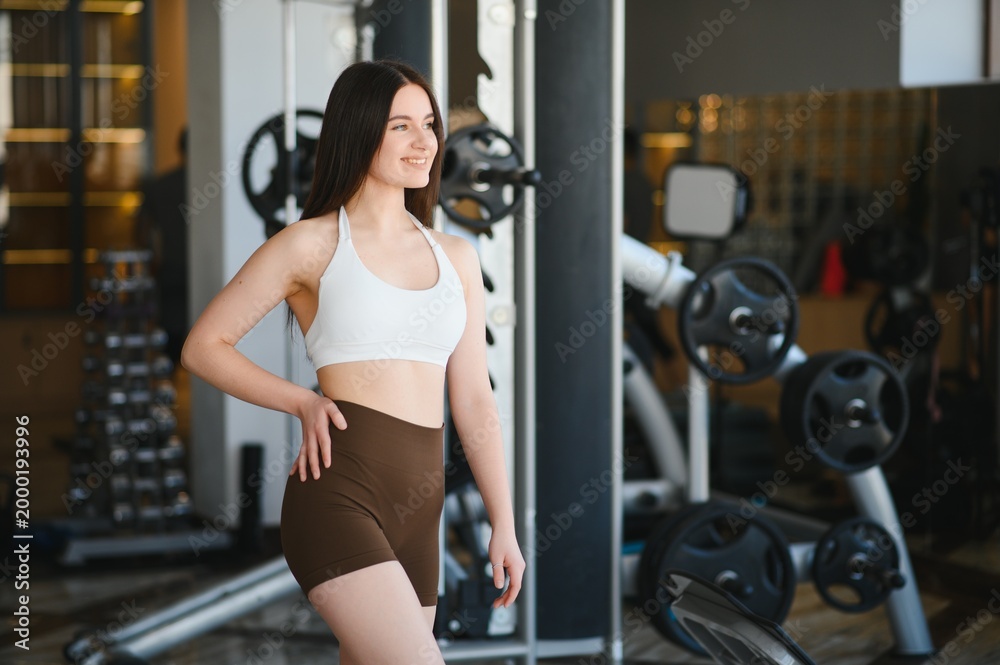 Fototapeta premium Young woman smiling while posing in gym