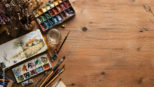 Top view of creative artist workspace with art supplies and copy space on wooden desk