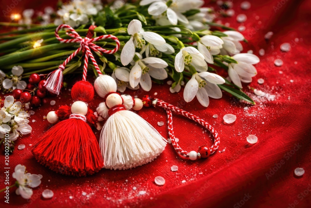 Fototapeta premium Festive Martenitsa decoration with fresh snowdrops on a bold crimson canvas symbolizing spring celebrations