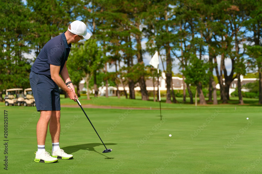 Fototapeta premium Man putting golf ball on green golf course.