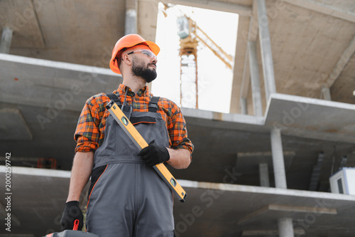 Fotografie Construction worker holding level tool at building site