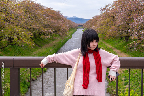 Woman Admiring Cherry Blossoms by River