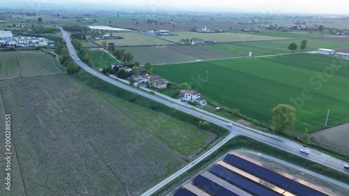 Drone footage captures a solar energy project under construction amidst agricultural fields and a nearby highway during golden hour