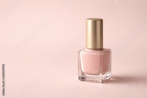 Cosmetic nail lacquer bottle positioned on muted pastel tone background with copy space
