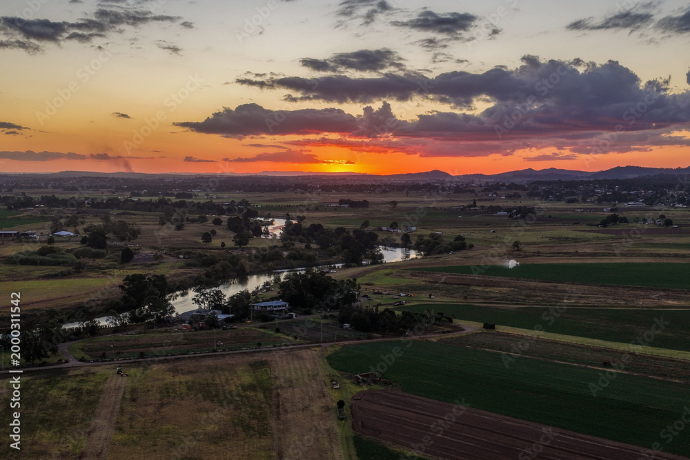 Fototapeta premium Aerial view of colourful sunset over Morpeth River and surrounding farmland in New South Wales, Australia. 