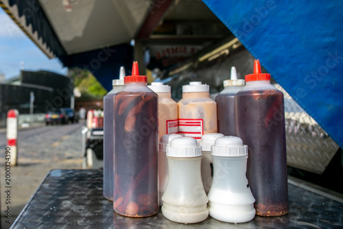 Φωτογραφία Assorted condiment squeeze bottles on a table, commonly used in fast-food outlets or food trucks for dispensing sauces such as ketchup, mustard, and mayonnaise