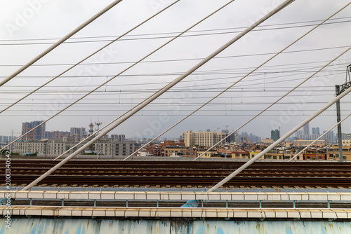 Railway tracks on cable stayed bridge with urban skyline in background in Guangzhou China modern transport infrastructure cityscape lines and perspective composition