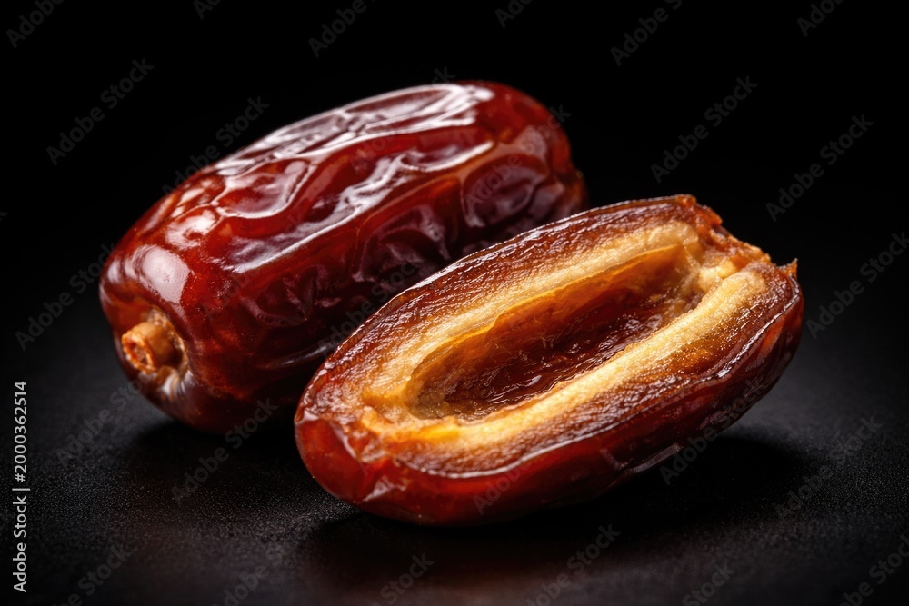 Fototapeta premium Close macro capture of whole date and a halved date with core removed under studio lighting on black background