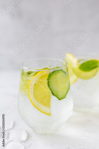 Detox water with cucumber, lime and mint in a glass on white marble. Bright, airy, and clean aesthetic with visible gas bubbles. Perfect for health, wellness, and hydration concepts. 