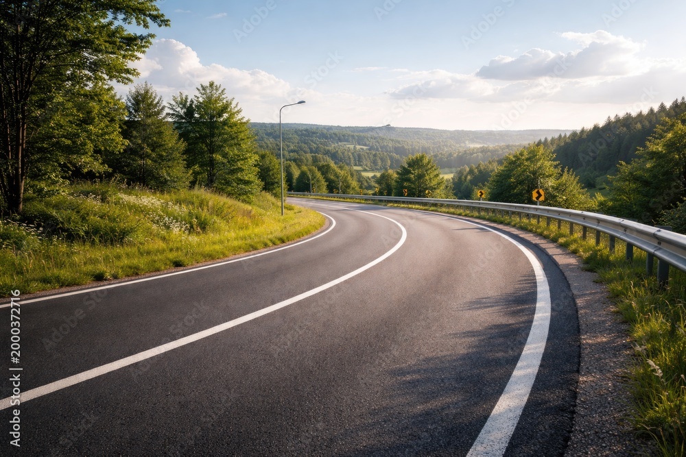 Fototapeta premium Open view of a clear bend along a refined pavement road with a crash barrier visible in the background