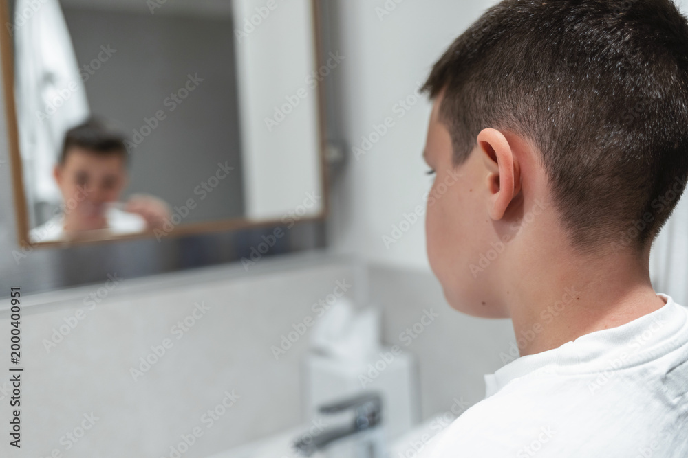 Fototapeta premium Little boy is brushing his teeth at the bathroom sink in the morning.