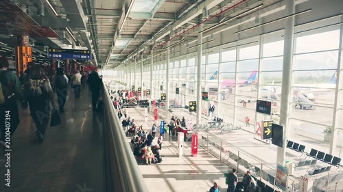 Tirana, Albania - 15th april, 2026:timelapse bustling panorama modern airport terminal with passengers sit waiting by gates. Transportation costs, summer travel flights. Motion blur intentional effect