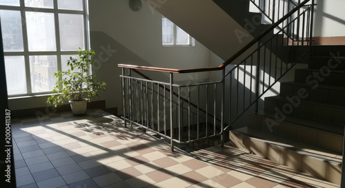 Staircase with metal railings in sunlit indoor hallway with potted plant