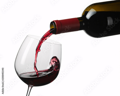 A bottle of red wine is being poured into a glass