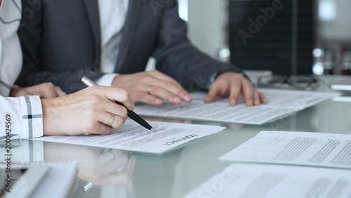 Valokuva Group of professional business people sitting at a meeting table, reading and discussing contract terms, financial agreements