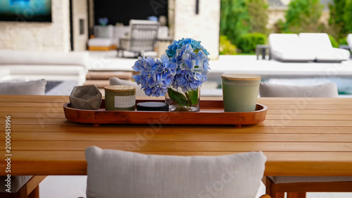 Obraz na plátne A wooden outdoor dining table featuring a decorative tray with blue hydrangeas,