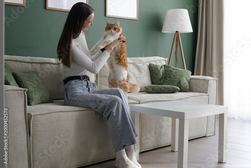 Happy woman and cat sitting on a sofa in a living room at home