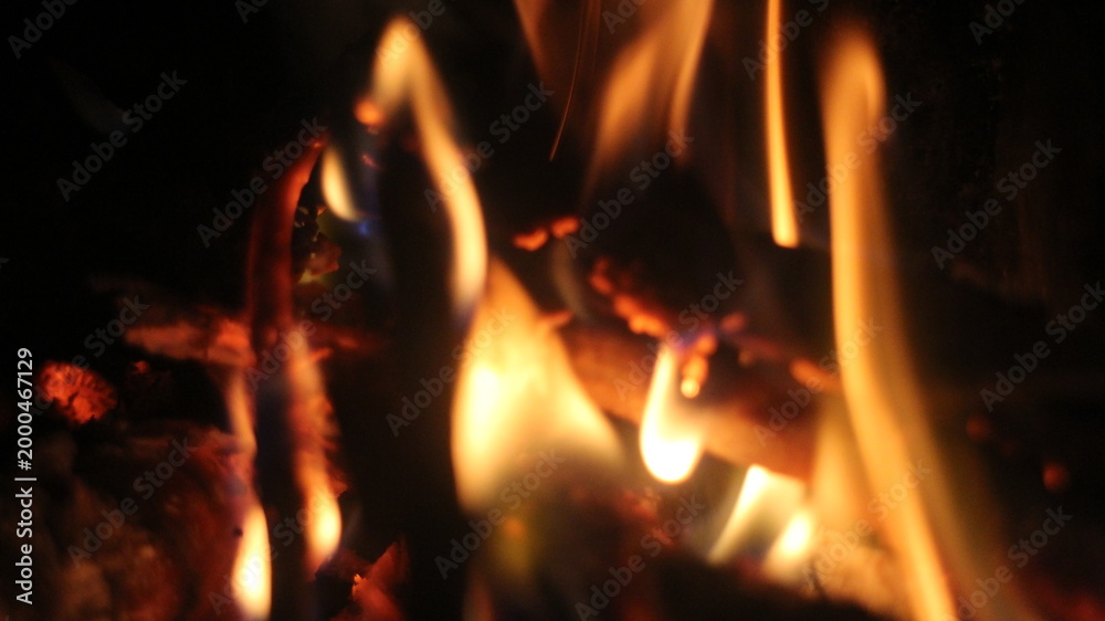 Fototapeta premium Burning log of firewood in fireplace. Close up abstract background Wood fire on black background