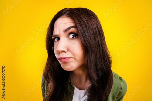 Skeptical young woman making doubtful face in a colorful studio portrait with yellow background