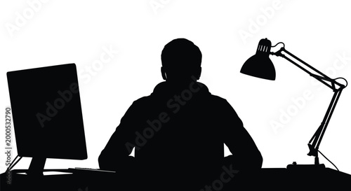 Silhouette of a person working at a desk with a computer and desk lamp