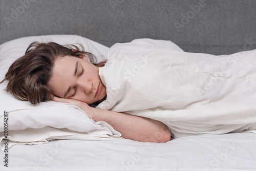 A teenager sleeps at home on the couch, the guy enjoys deep sleep and rest, daily routine.