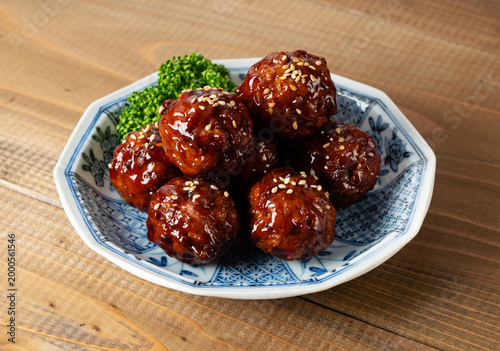 Delicious glazed meatballs with sweet and sour sauce, sesame seeds and parsley on a ceramic plate