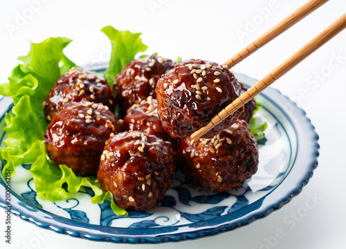 Canvastavla Chopsticks lifting a delicious glazed Japanese meatball with sesame seeds on a w