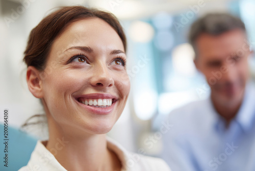 Free Download Woman smiling naturally showing healthy teeth while dentist consults with her, bright dental clinic background softly blurred, clinical lighting, - GFXLoad