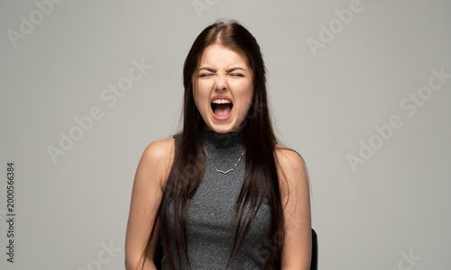 Fotografija Young woman shouting and screaming in frustration, expressing anger, pain, and o