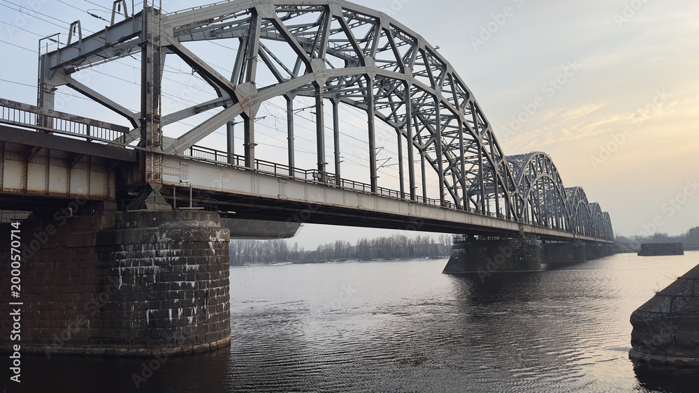 Fototapeta premium Sunset landscape with a bridge over the river, evening lights and reflections in the water