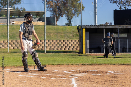 Foto Male baseball players standing at home plate infield, catcher wearing gear holdi