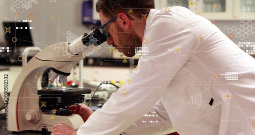 Leaning scientist in white coat blue goggles adjusting microscope stage at lab bench with HUD