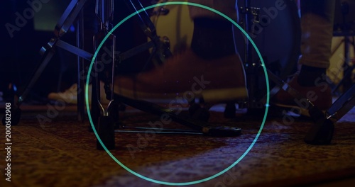 Showing drummer foot pressing bass pedal on rug at rehearsal with turquoise overlay, brown shoe